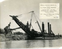 One black and white photograph of a dipper dredge at work