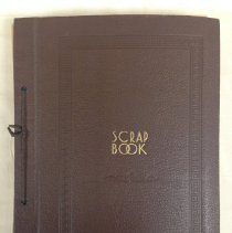 Brown hardcover scrapbook bound with string and "Scrapbook" in gold