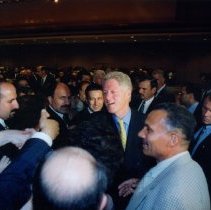 Color photograph of Bill Clinton shaking hands with crowd of people