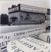 Black and white photo of storefront having new awnings installed