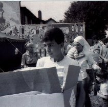 Black & whit photo of young man carrying box with people in background