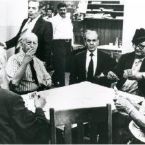 Black and white photo of men around a table playing cards