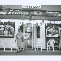 Black & white photo of bakery storefront with three men outside