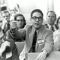 Black and white image of Farouk El-Baz talking with men seated around him