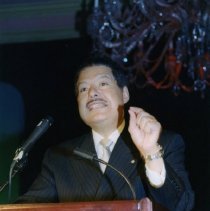 Color photo of man mid-speech at podium