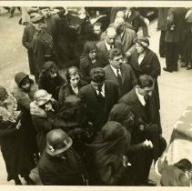 Sepia toned photo of mourners in black following casket with American flag