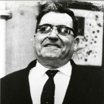 Black and white photo of man in suit and tie and horn-rimmed glasses
