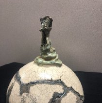 Clay sculpture of cracked dome and abstract figure on top