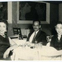 Black and white photograph of 3 people sitting at a table in a restaurant