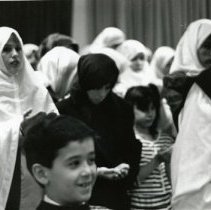 Photo of women and children standing and praying at mosque