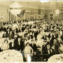 Black and white photo of large banquet hall filled with people at tables