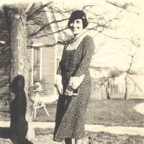 1930-02 sepia tone photo of woman standing in front of a house