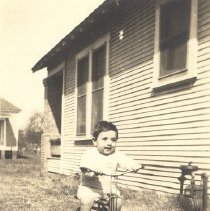 1932-gfk sepia tone photo of toddler on tricycle in front of house