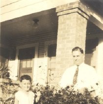 1933-jkk-i-ii sepia tone photo of man and child in front of house