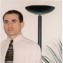 Color photo of man standing in front of a lamp