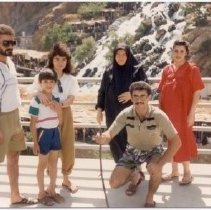 Color photo of family standing in front of railing with waterfall behind