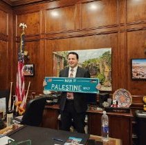 Mayor Sayegh holding the Palestine way street sign