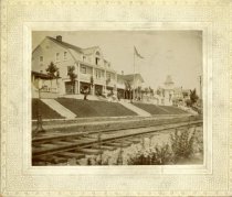 Men and women on porch of The Emmet, railroad tracks in front