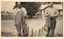 Two men holding string of dead squirrels
