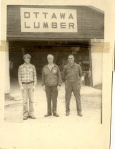 Three men in front of a carpenter's shop.