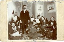 Photograph of people singing in the Shay living room about 1898-1900.