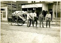 Photograph of five men pulling a firehose cart in downtown Harbor Springs.