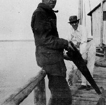 Men on a dock with a handsaw, photograph, ca. 1915.