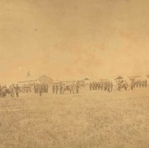 Group of soldiers in formation beside gun carriages in a large field, photograph, photograph, ca. 1915.
