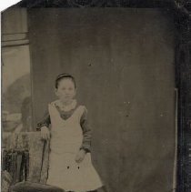 Unidentified girl wearing white pinafore, ca.1865.