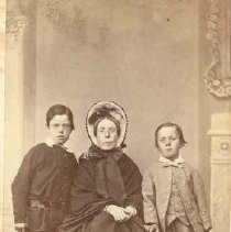 Mrs. Douglas with 2 young boys; she is wearing a wintercoat and a stiff bonnet, ca. 1875.