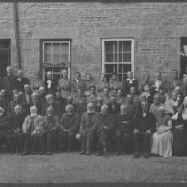 Group of elderly residents in front of Wellington County House of Industry and Refuge; 2 residents identified as Mabel Clarke and Clarissa Ostic, photograph ca. 1900.