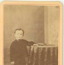 Young boy standing beside a table, photograph, ca. 1875.