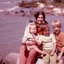 ph 16114: Woman with three children, at beach. On reverse "Sheila and her