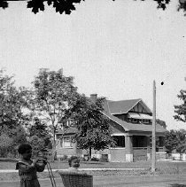 Girl pushing baby stroller along Queen Street, Mount Forest, photograph, ca. 1920.