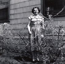 PH 23718 Eleanore Smith, standing next to house, shrubs. ca.1960