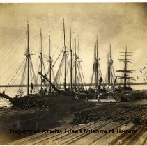 Photograph of ships and lumber at the docks.