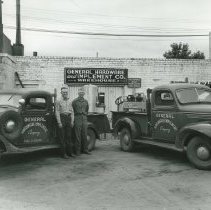General Hardware exterior with two cars and two men in front.