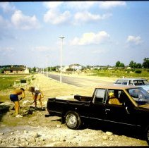 Two people digging behind a car on Harvard Road.