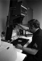Unidentified police officer operating photography lab equipment.