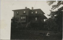 [Children and dog on lawn by residence]