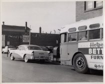 A car parked at a bus stop during the mid-20th century