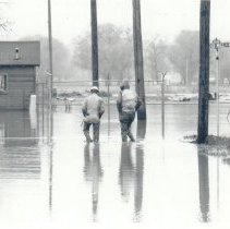 Two Littleton Streets Div. employees walk along flooded Old Mill St. April