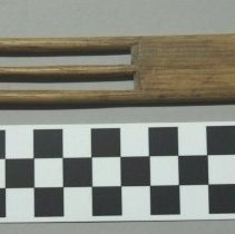 Wooden cord threader with central spindle.