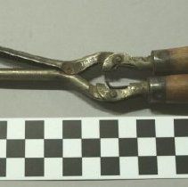 Curling iron with red-varnished wooden handles.