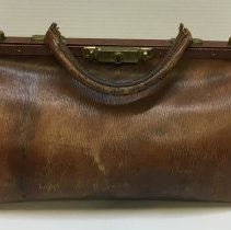Brown leather satchel with brass-colored metal lock and side clasps