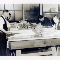 [Men working at a large table]