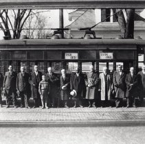 Group standing in front of electric streetcar, 1891-1931