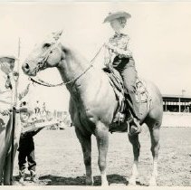 man and little boy at a microphone welcoming a woman on horseback
