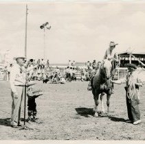 Joan Shoemarker dismounting horse; Petey Stark at the microphone