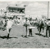 Joan Shoemarker dismounting horse; Petey Stark at the microphone